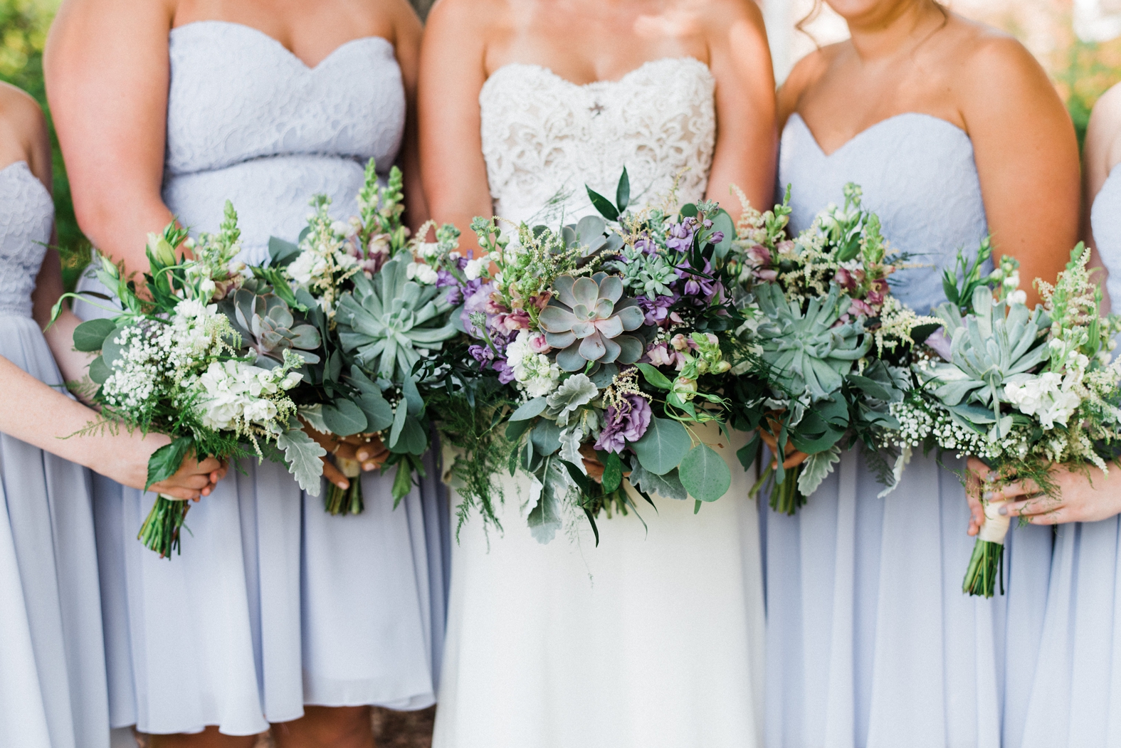 Bride and bridesmaids in light purple lavender dresses holding purple bouquets with succulents and silver dollar eucalyptus