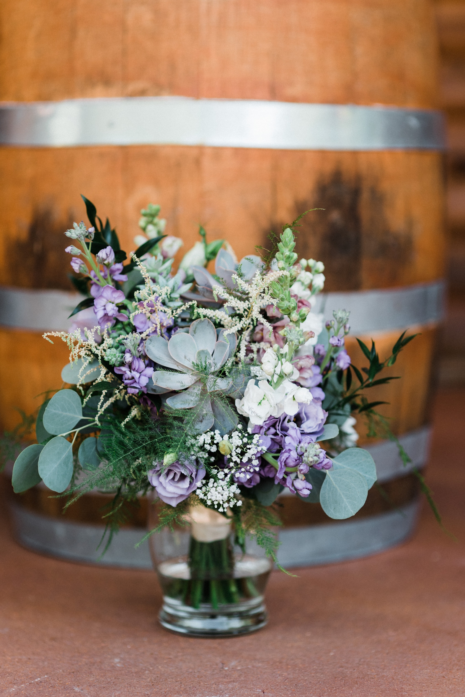 Purple, white, and lavender bridal bouquet with succulents, silver dollar eucalyptus, and greenery; wedding flowers