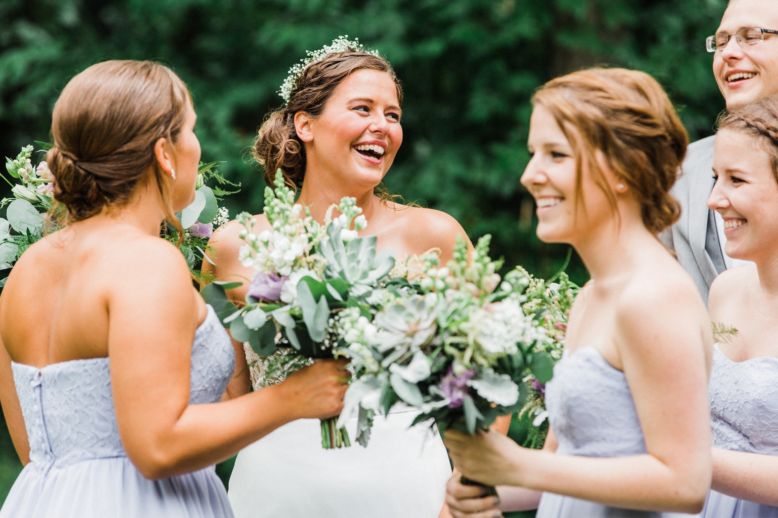 Bride in baby's breath flower crown laughing with bridesmaids in light purple lavender dresses. Purple bridesmaids bouquets with succulents and eucalyptus.