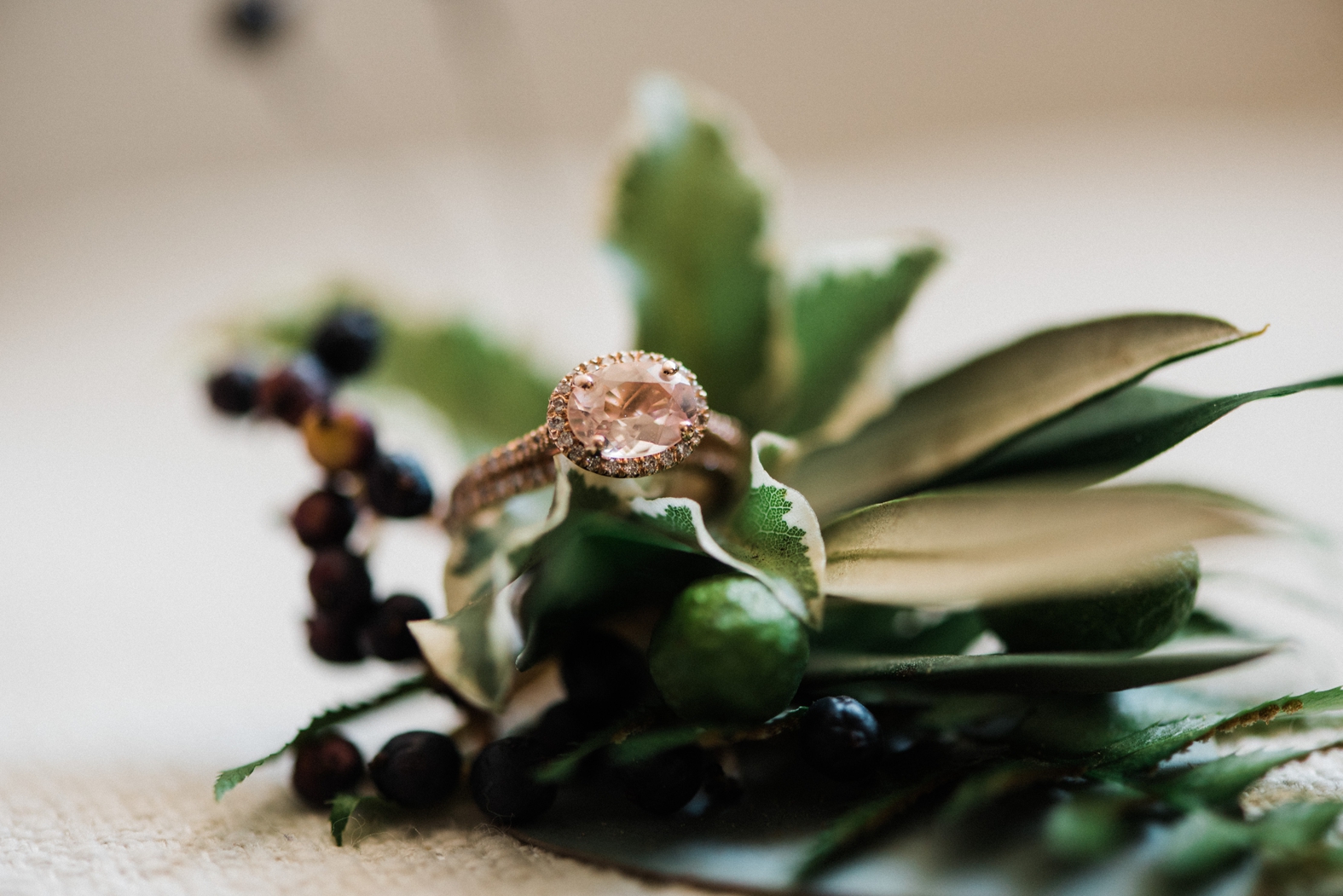 Morganite and rose gold engagement ring and wedding band on greenery boutonniere