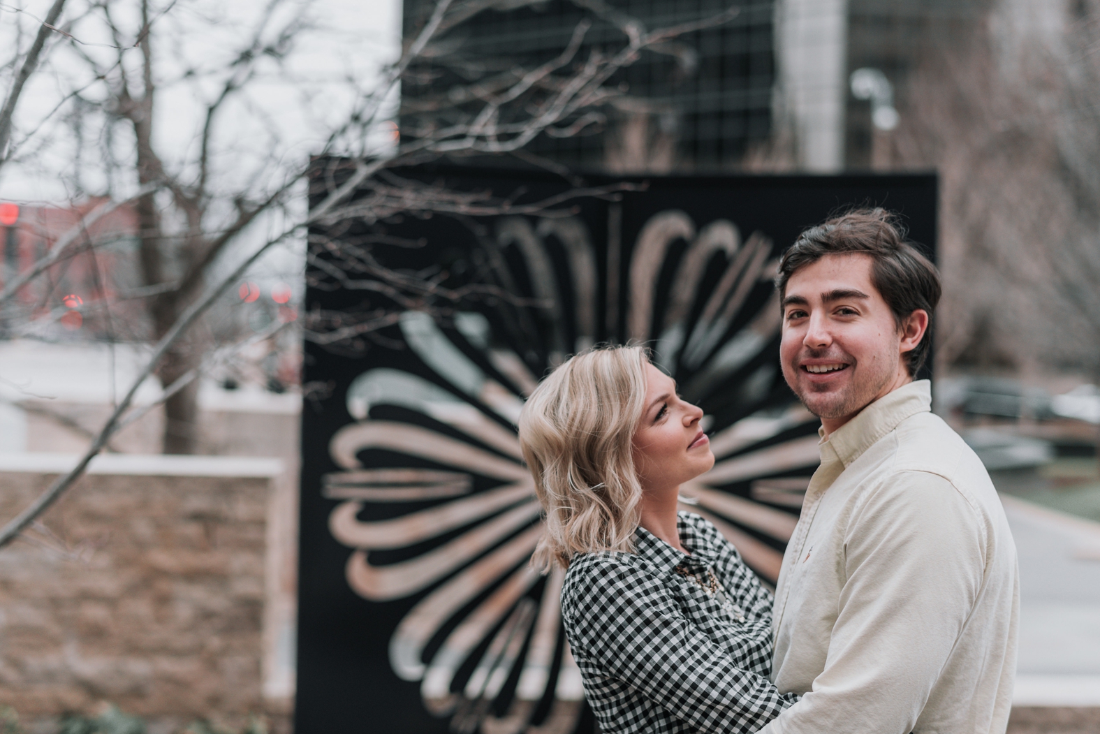 Bride to be looks adoringly at her groom as they embrace at their downtown St. Louis winter engagement photo session.