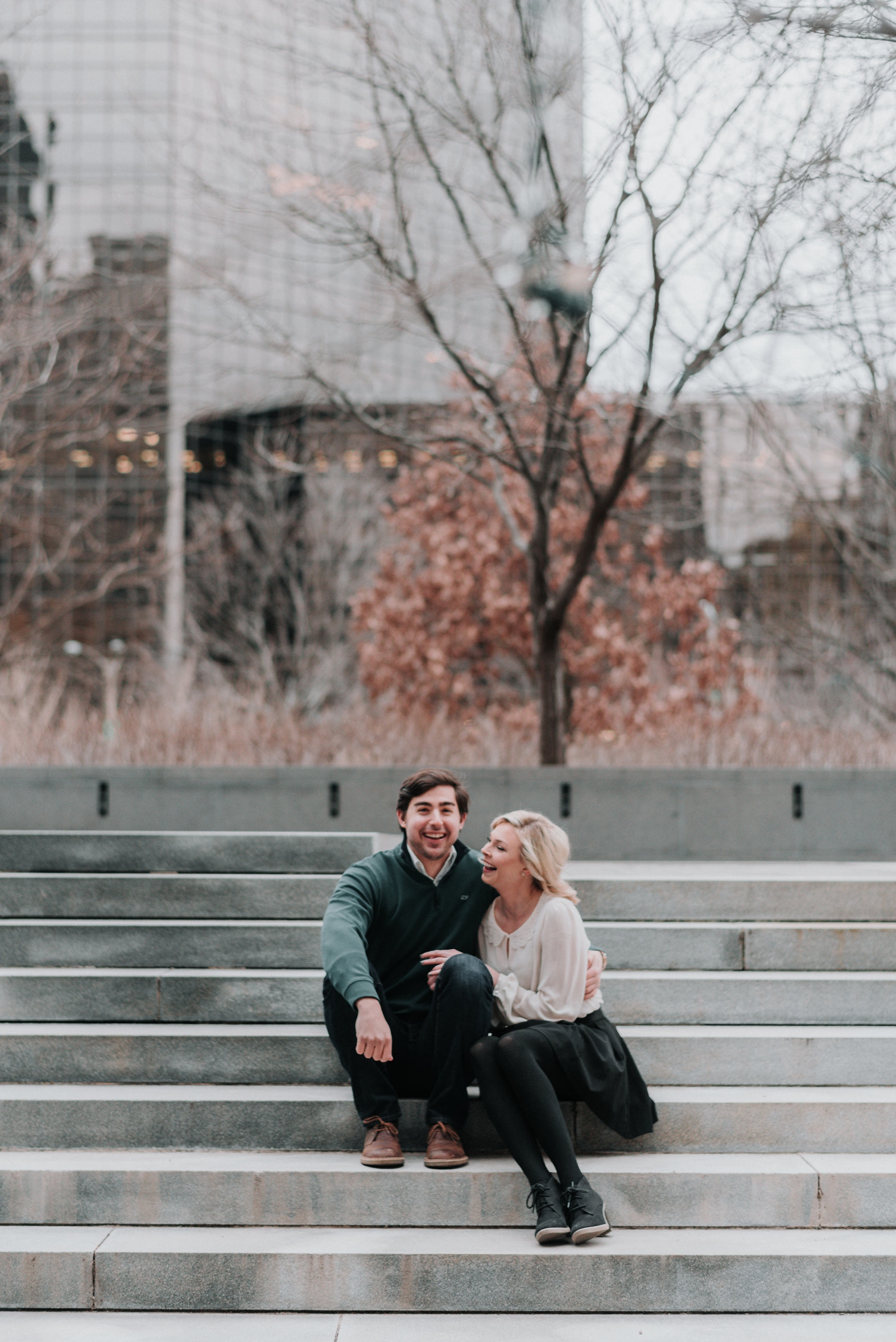 Bride and groom hug close and laugh on steps in downtown St. Louis during their winter engagement photo session.