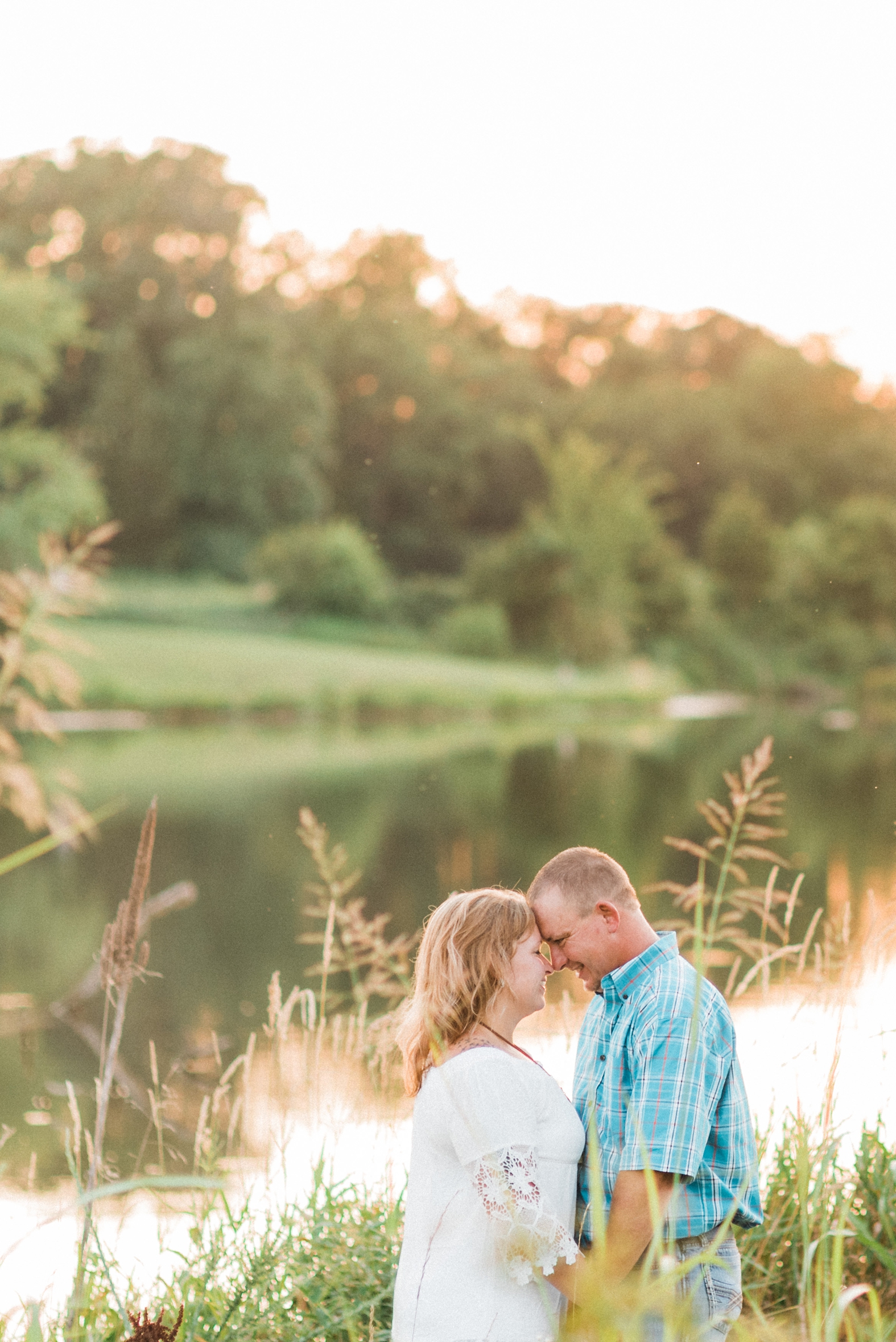 Bride and groom touch foreheads and embrace at their sunset engagement shoot in Broemmelsiek Park in St. Charles, MO.