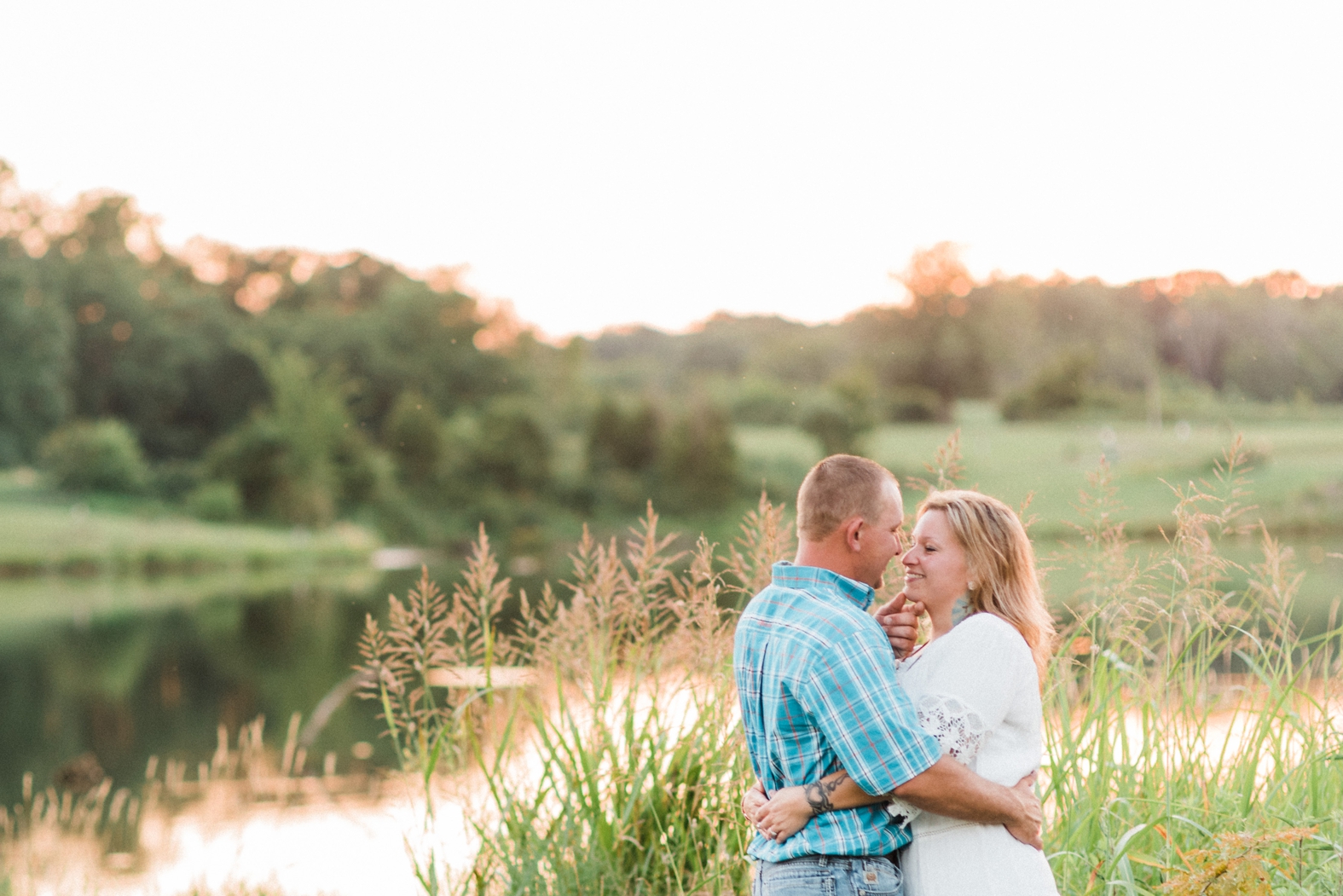 Bride and groom embrace closely for their engagement photos at Broemmelsiek Park in St. Charles, MO near the beautiful water.